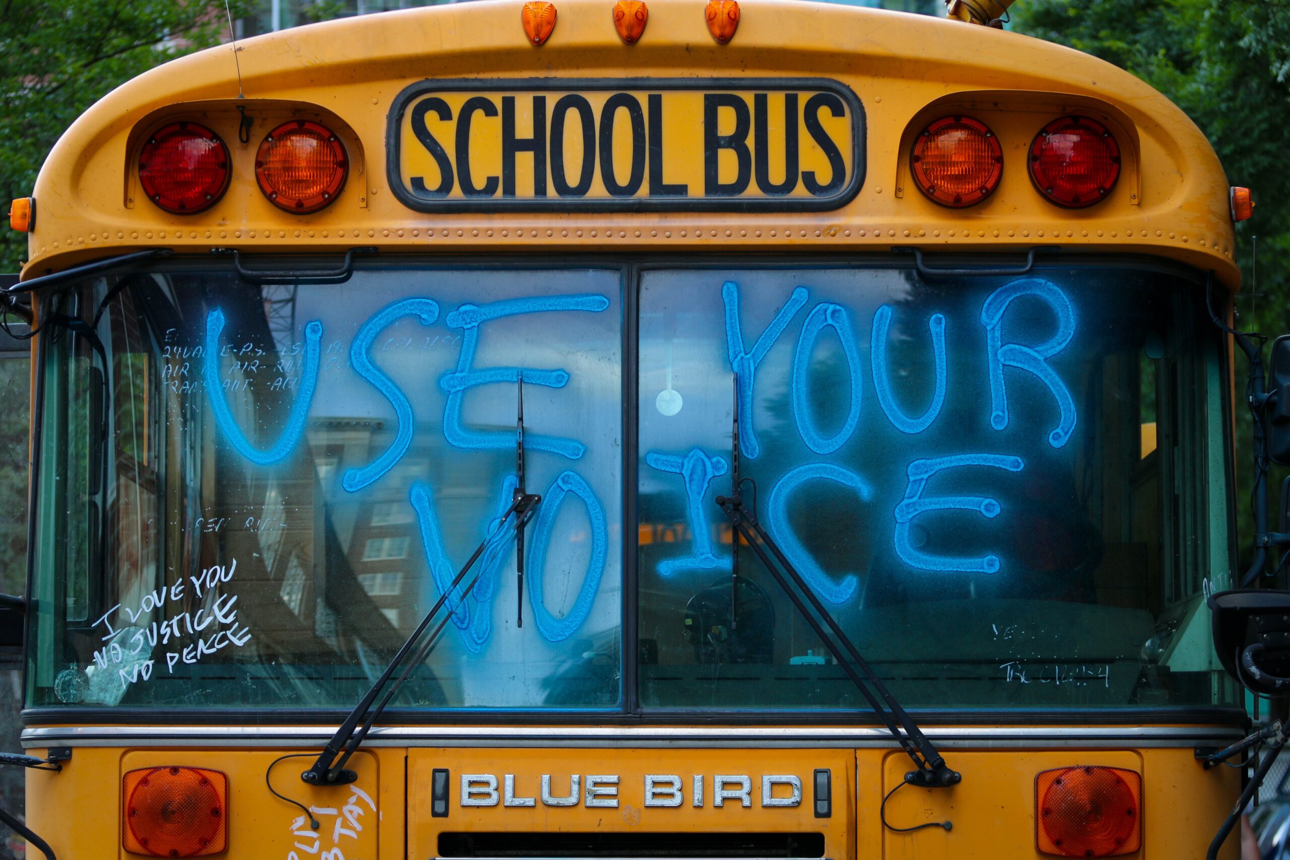 a school bus with "use your voice" spray painted on it